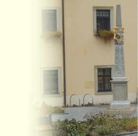 Platz mit Postmeilensäule, gerahmt von Staudenpflanzungen